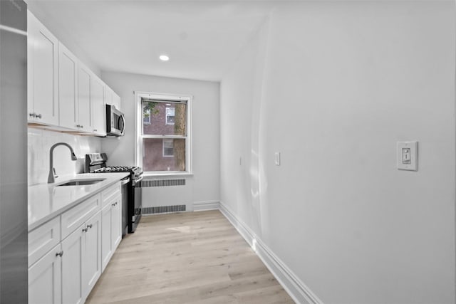 kitchen with light countertops, appliances with stainless steel finishes, a sink, and white cabinets