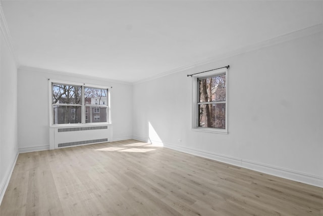 spare room featuring radiator, plenty of natural light, light wood-type flooring, and ornamental molding