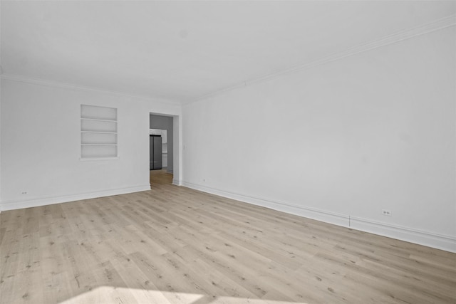 unfurnished room featuring light wood-type flooring, built in shelves, baseboards, and crown molding