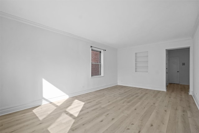 unfurnished room featuring light wood finished floors, ornamental molding, baseboards, and built in features