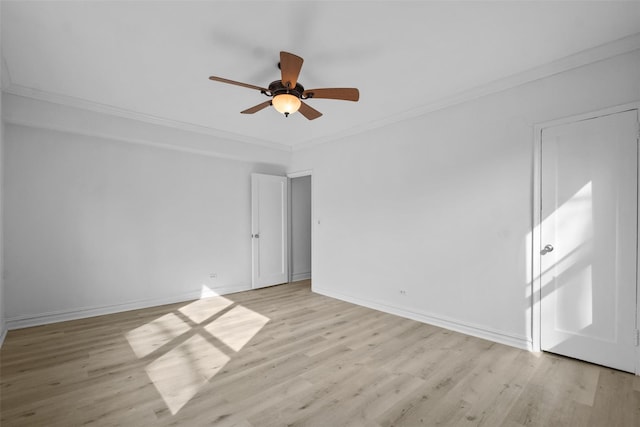 spare room featuring ornamental molding, light wood-style flooring, and baseboards