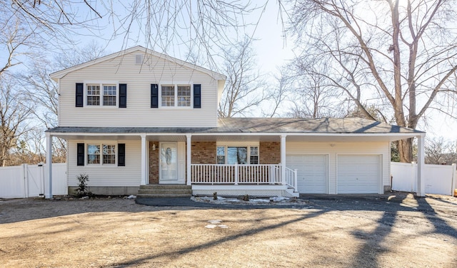 view of front of property featuring dirt driveway, a porch, fence, and a garage