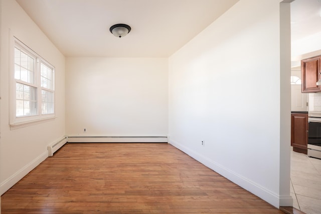 empty room featuring baseboard heating, a baseboard radiator, light wood-style flooring, and baseboards