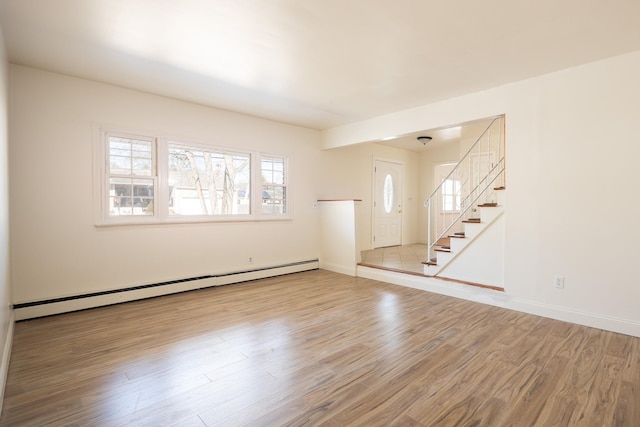 spare room with a baseboard radiator, plenty of natural light, light wood finished floors, and stairs