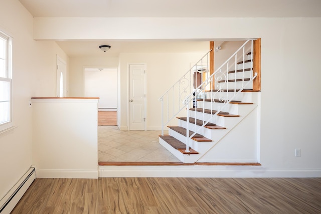 stairway with baseboards, a baseboard heating unit, and wood finished floors