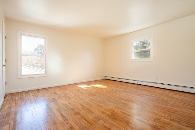 unfurnished room featuring a wealth of natural light, baseboards, light wood-style flooring, and baseboard heating