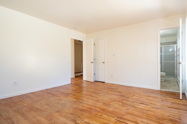 unfurnished bedroom with light wood finished floors, ensuite bath, and baseboards