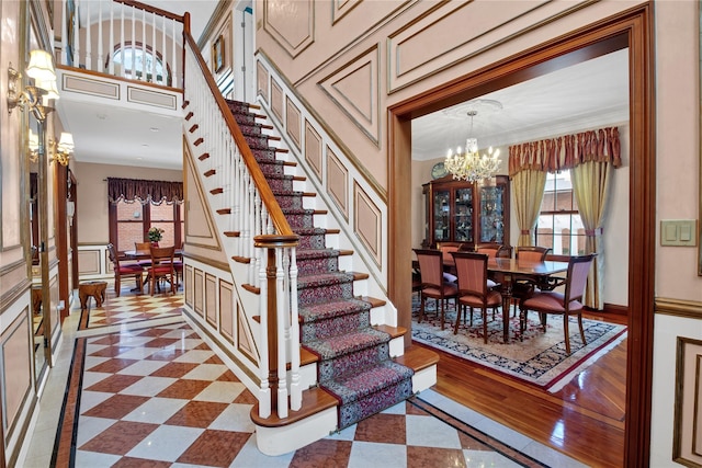 stairway with a chandelier and ornamental molding