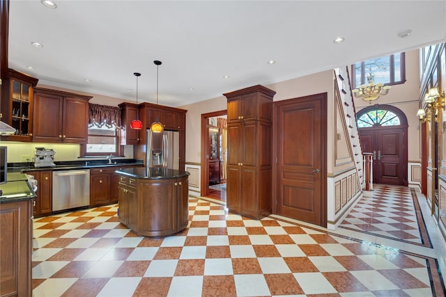 kitchen featuring dark countertops, a kitchen island, glass insert cabinets, hanging light fixtures, and stainless steel appliances