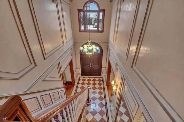 entryway with a notable chandelier, a decorative wall, and tile patterned floors