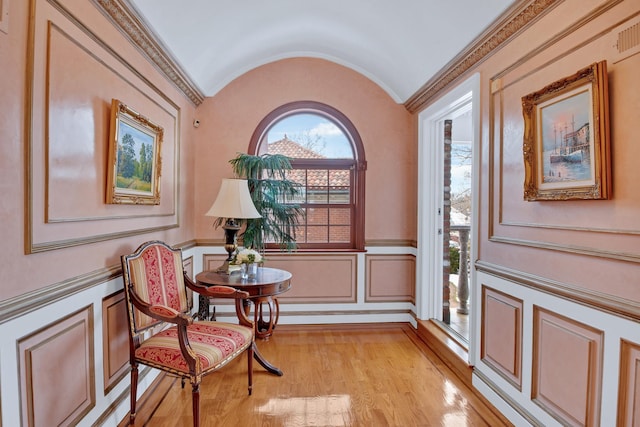 sitting room featuring lofted ceiling, light wood-style flooring, and wainscoting