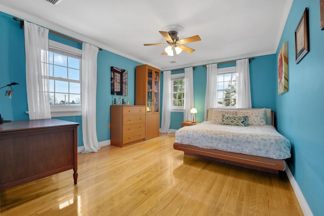 bedroom with crown molding, baseboards, a ceiling fan, and light wood-style floors