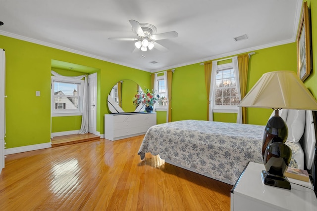 bedroom featuring light wood-style flooring, multiple windows, ornamental molding, and visible vents