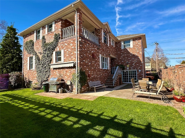 rear view of house featuring a patio area, a yard, brick siding, and fence