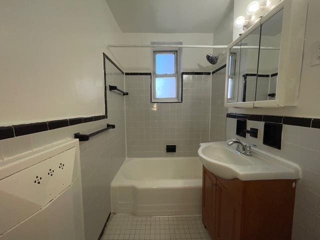 bathroom featuring shower / washtub combination, tile walls, tile patterned flooring, washer / dryer, and vanity