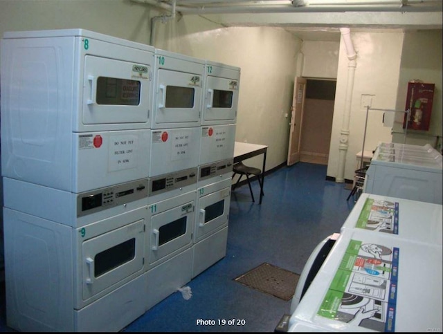 kitchen with stacked washer and clothes dryer and concrete flooring