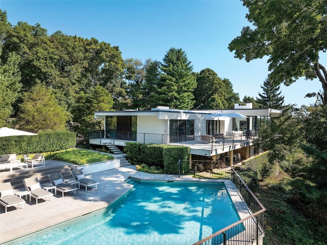 outdoor pool with stairs, a wooden deck, and a patio area