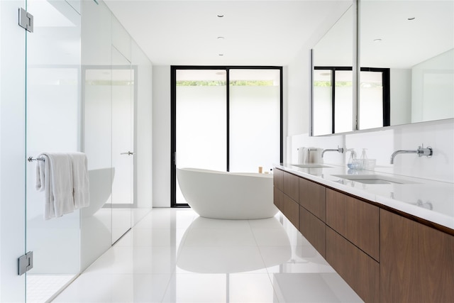 full bathroom featuring tile patterned floors, a sink, a freestanding tub, and a shower stall
