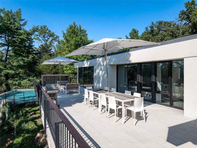 view of patio / terrace with outdoor dining area, fence, and a fenced in pool