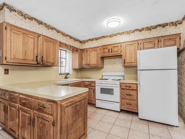 kitchen with light tile patterned floors, white appliances, a sink, light countertops, and wallpapered walls