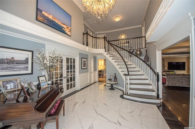 entrance foyer featuring marble finish floor, crown molding, a notable chandelier, stairway, and a high ceiling