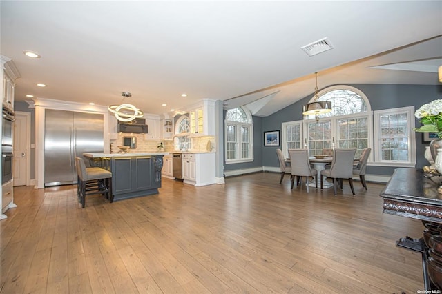 kitchen featuring stainless steel appliances, hanging light fixtures, glass insert cabinets, and a center island