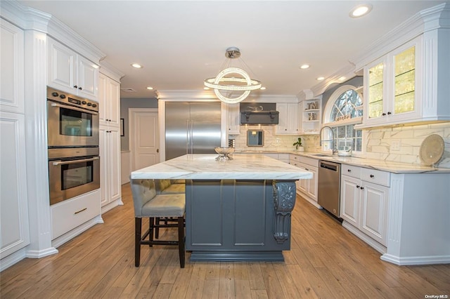 kitchen featuring appliances with stainless steel finishes, white cabinets, glass insert cabinets, and a kitchen island