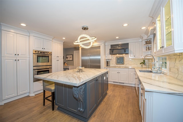 kitchen featuring stainless steel appliances, a kitchen island, white cabinetry, and pendant lighting