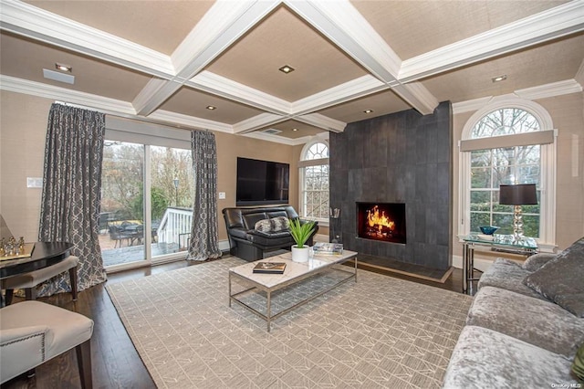 living area with a large fireplace, coffered ceiling, beamed ceiling, and wood finished floors