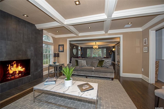 living room featuring dark wood-style flooring, a tiled fireplace, coffered ceiling, and beam ceiling