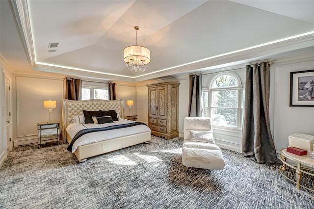 carpeted bedroom featuring a tray ceiling, lofted ceiling, visible vents, baseboard heating, and a chandelier