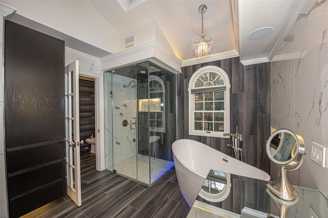 full bath with tile walls, a freestanding bath, ornamental molding, a stall shower, and vaulted ceiling