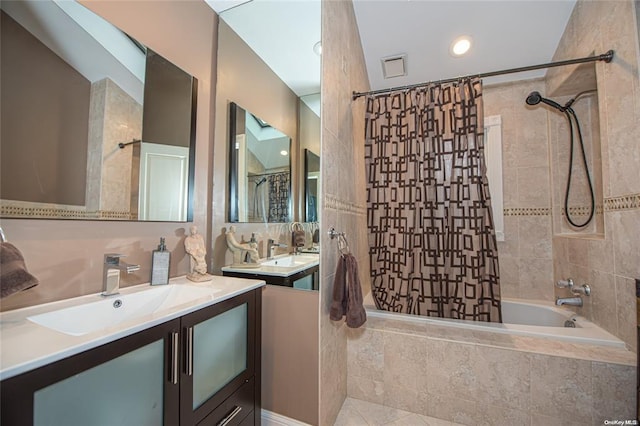 full bath featuring tiled shower / bath combo, visible vents, two vanities, and a sink