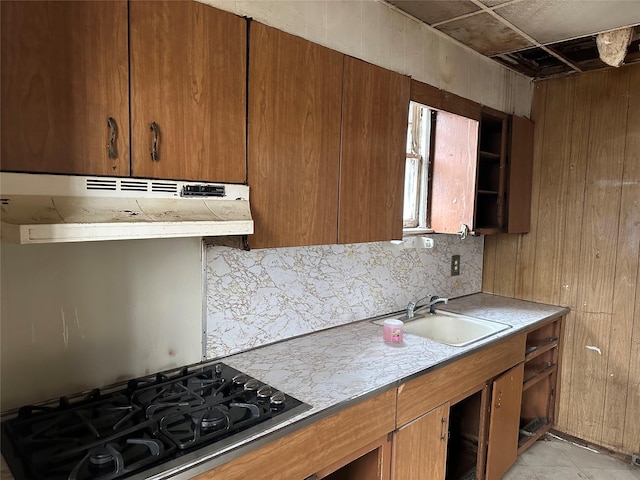 kitchen with under cabinet range hood, a sink, open shelves, tasteful backsplash, and cooktop