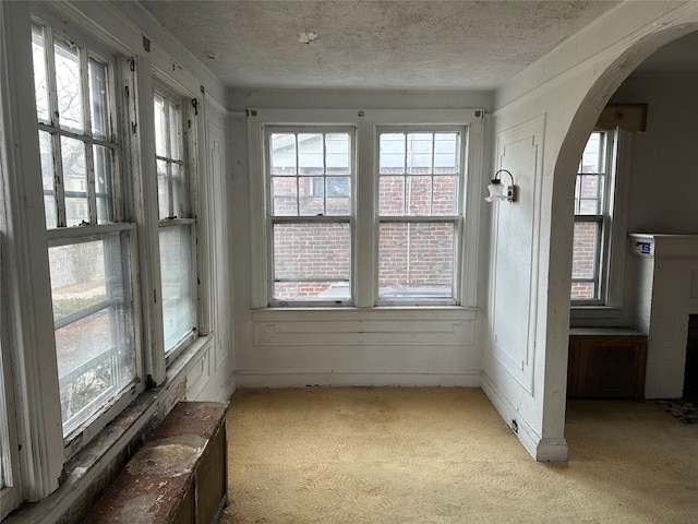 unfurnished sunroom featuring arched walkways