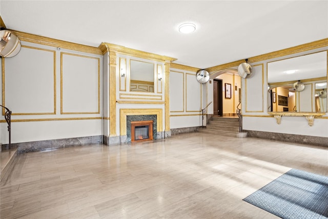 unfurnished living room featuring stairs, arched walkways, and a high end fireplace