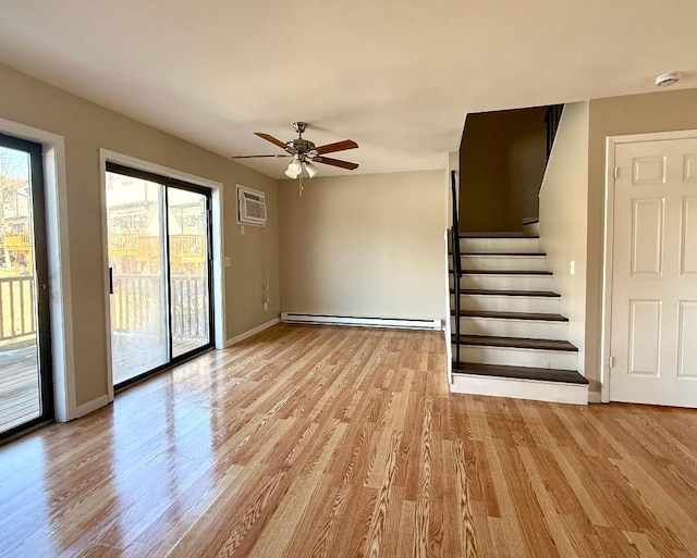 unfurnished living room featuring light wood finished floors, stairway, baseboard heating, and a wealth of natural light