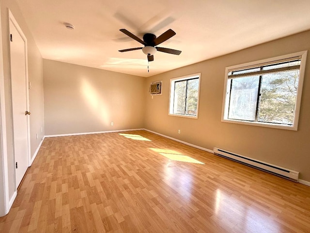 unfurnished bedroom featuring a wall unit AC, a baseboard radiator, light wood-style flooring, a ceiling fan, and baseboards