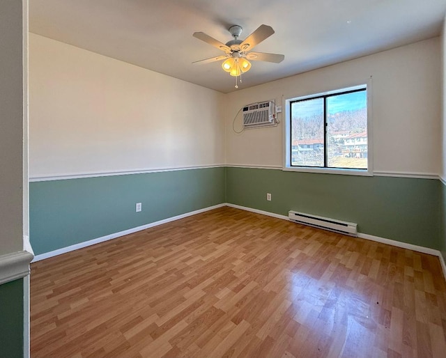 unfurnished room with ceiling fan, baseboard heating, wood finished floors, and baseboards