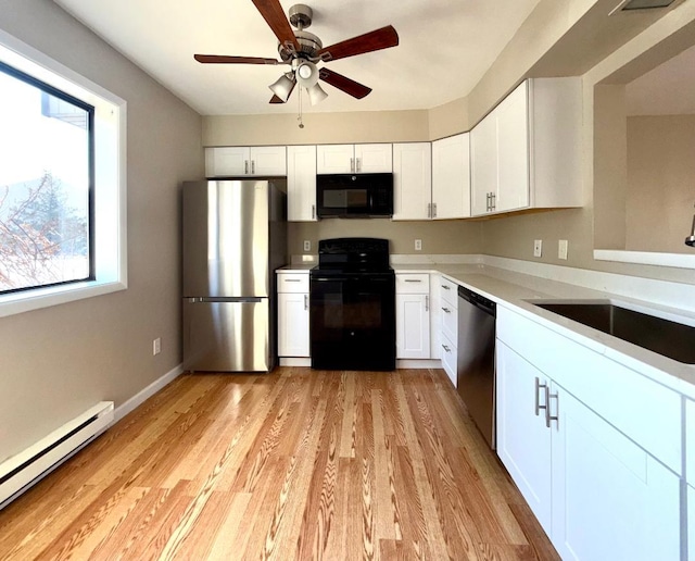 kitchen with a baseboard heating unit, a sink, white cabinets, light countertops, and black appliances