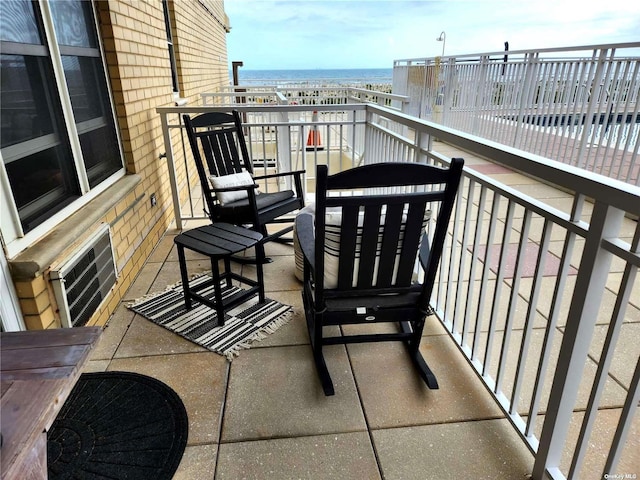 balcony featuring a water view and a wall mounted air conditioner