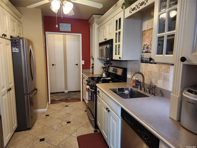 kitchen with a sink, light countertops, appliances with stainless steel finishes, tasteful backsplash, and glass insert cabinets