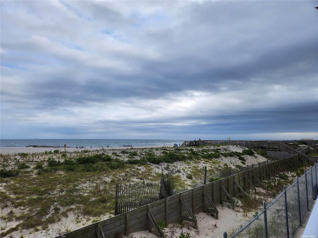 property view of water with fence and a beach view