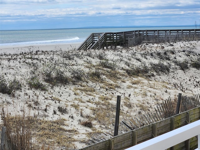 view of water feature with a beach view and fence