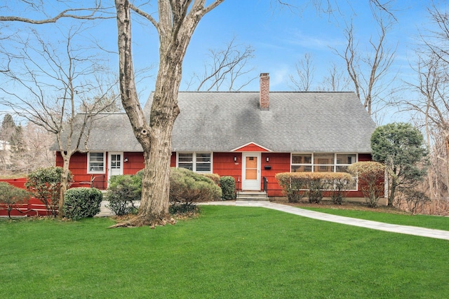 view of front of home featuring a shingled roof, a chimney, and a front yard