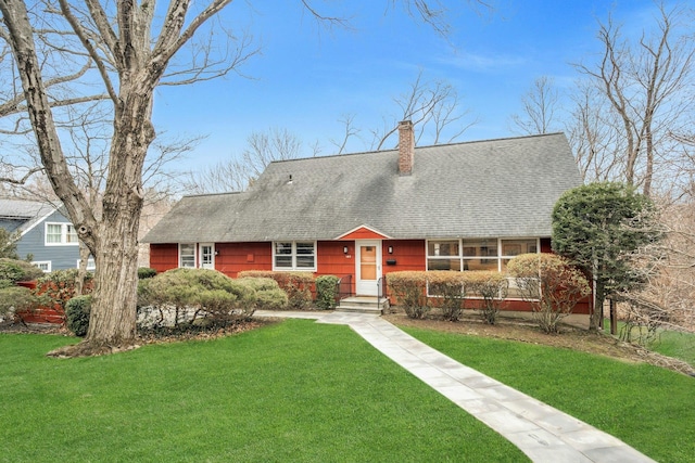 view of front of home with a front yard, roof with shingles, and a chimney