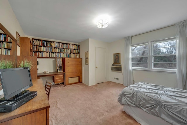 bedroom featuring built in desk, a wall unit AC, visible vents, and light colored carpet