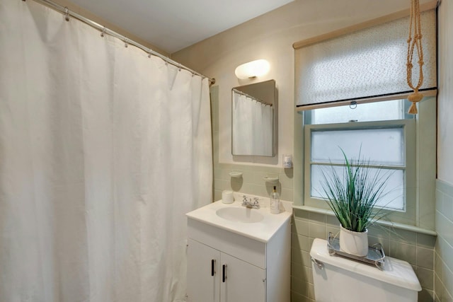 bathroom featuring toilet, tile walls, and vanity