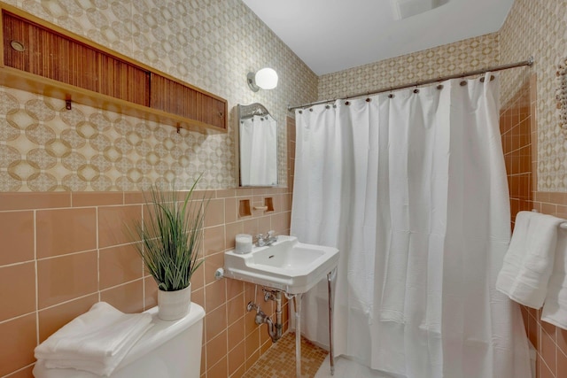 full bath featuring toilet, wallpapered walls, a shower with curtain, and tile walls