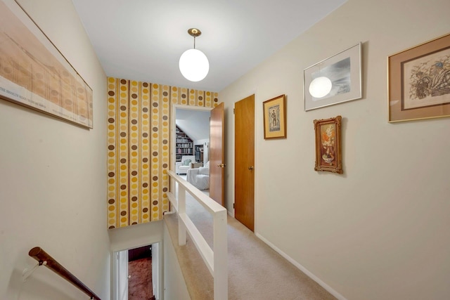 corridor featuring carpet flooring, an upstairs landing, and baseboards